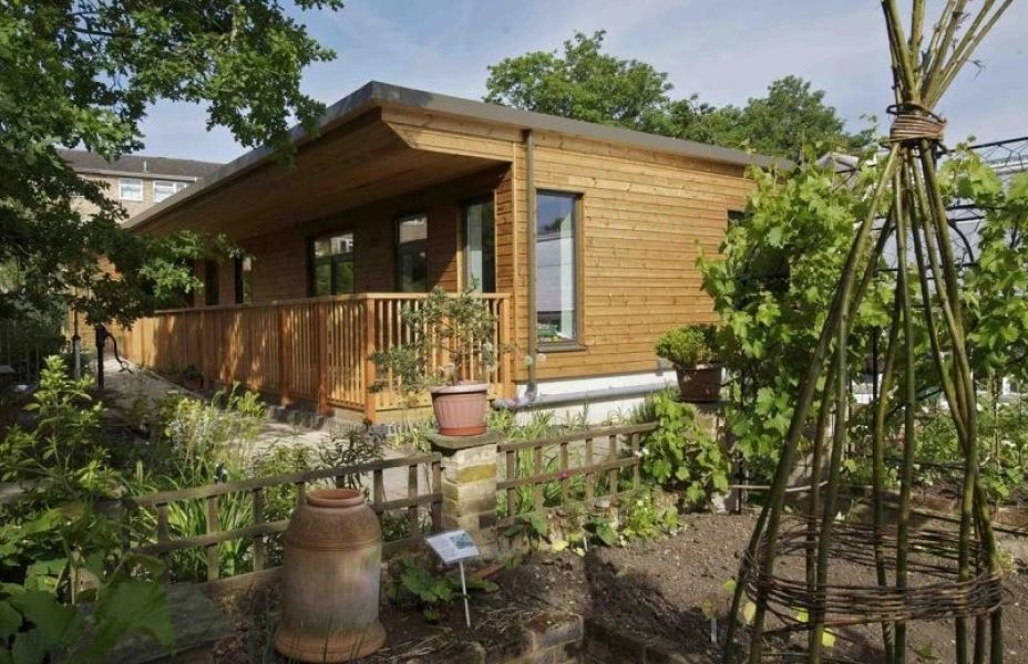 a wooden cabin set against planted flowers and vegetables